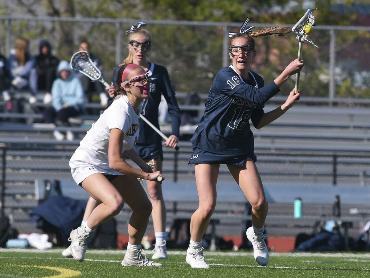 Wilton’s Isabel DiNanno (18) controls the ball on a draw while Greenwich’s Noey Johnson (3) defends during a girls lacrosse game in Greenwich on Thursday.