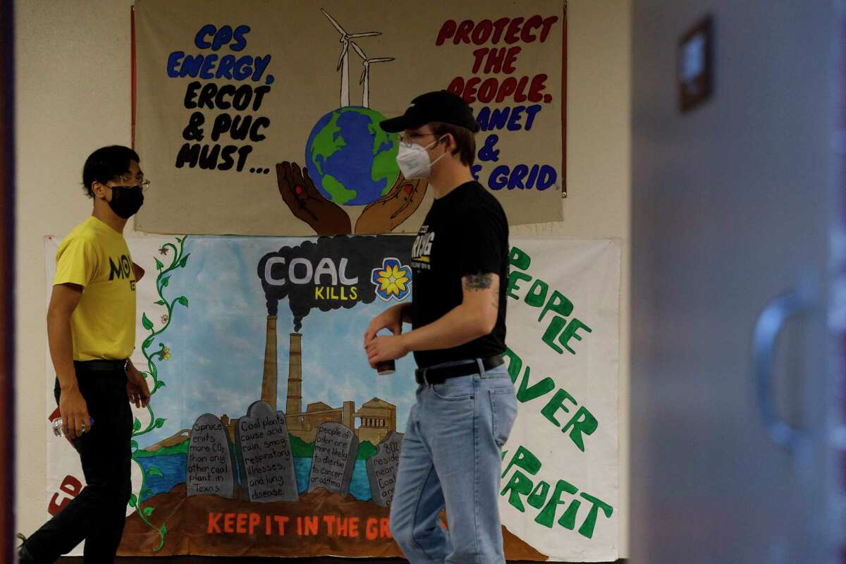 People walk by protest banners after a panel discussion between San Antonio climate activists and Rudy Garza, interim CEO of CPS Energy, about the future of J.K. Spruce Power Plant Thursday evening, April 28, 2022, at Woodlawn Pointe Auditorium.