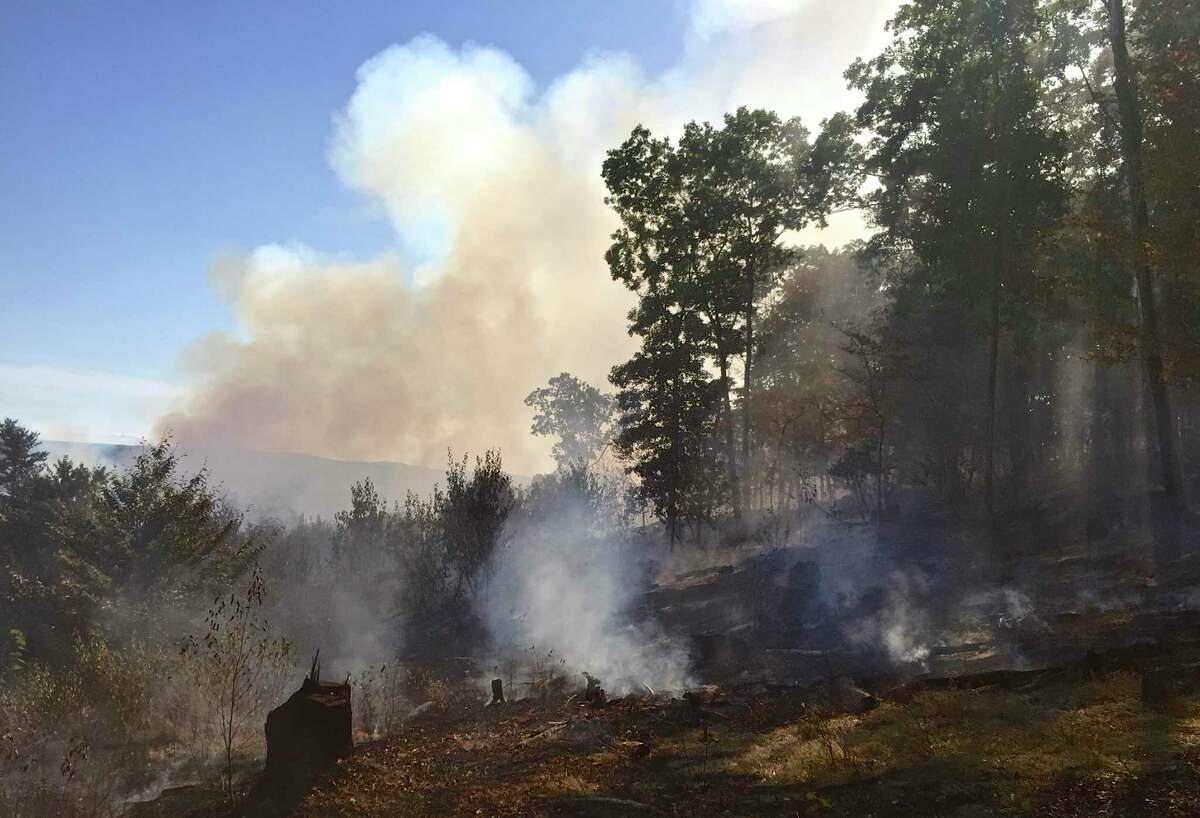 A burnt area is backed by the still burning fast-moving brush fire behind it on Saturday afternoon along Beaver Bog Road, in New Fairfield. The fire grew from about 3 to 10 acres in just over an hour. . Saturday, September 5, 2015, in New Fairfield, Conn.