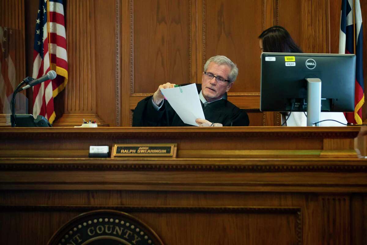 Tarrant County Judge Ralph Swearingin Jr. speaks to a member of his staff in his Fort Worth courtroom. Defendants appear in court to dispute or settle debt lawsuits.