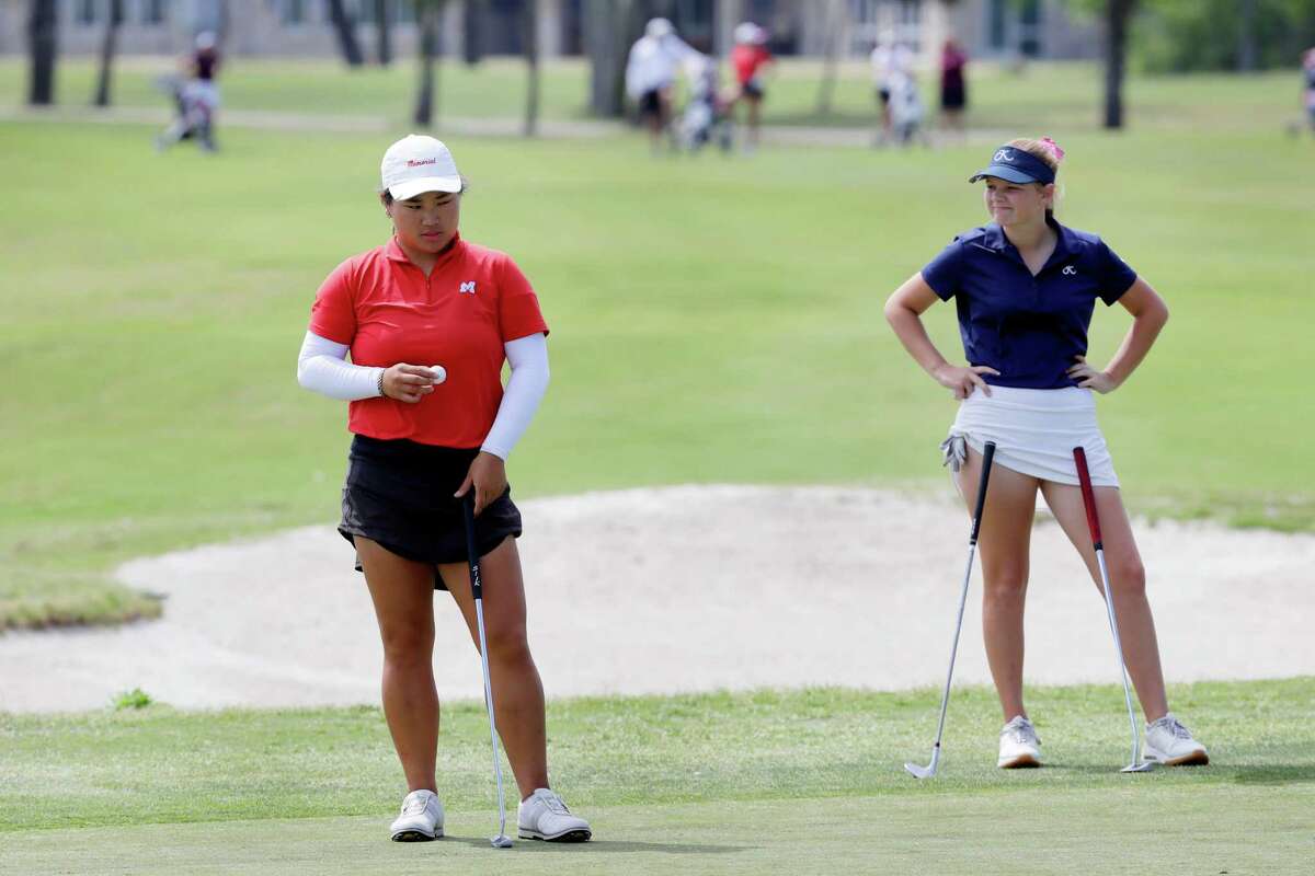 Caithilyn Lee of Houston Memorial, left, looks to place her ball on the 18th green as Khole Jones of Kingwood, right, waits during the second round of the Region III-6A Girls Golf Tournament held at Eagle Pointe Golf ClubTuesday, Apr. 19, 2022 in Mont Belvieu, TX.