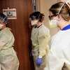 Nurses at Adventist Health hospital in Sonora, Calif. put on PPE before checking on a COVID patient in March, 2022.
