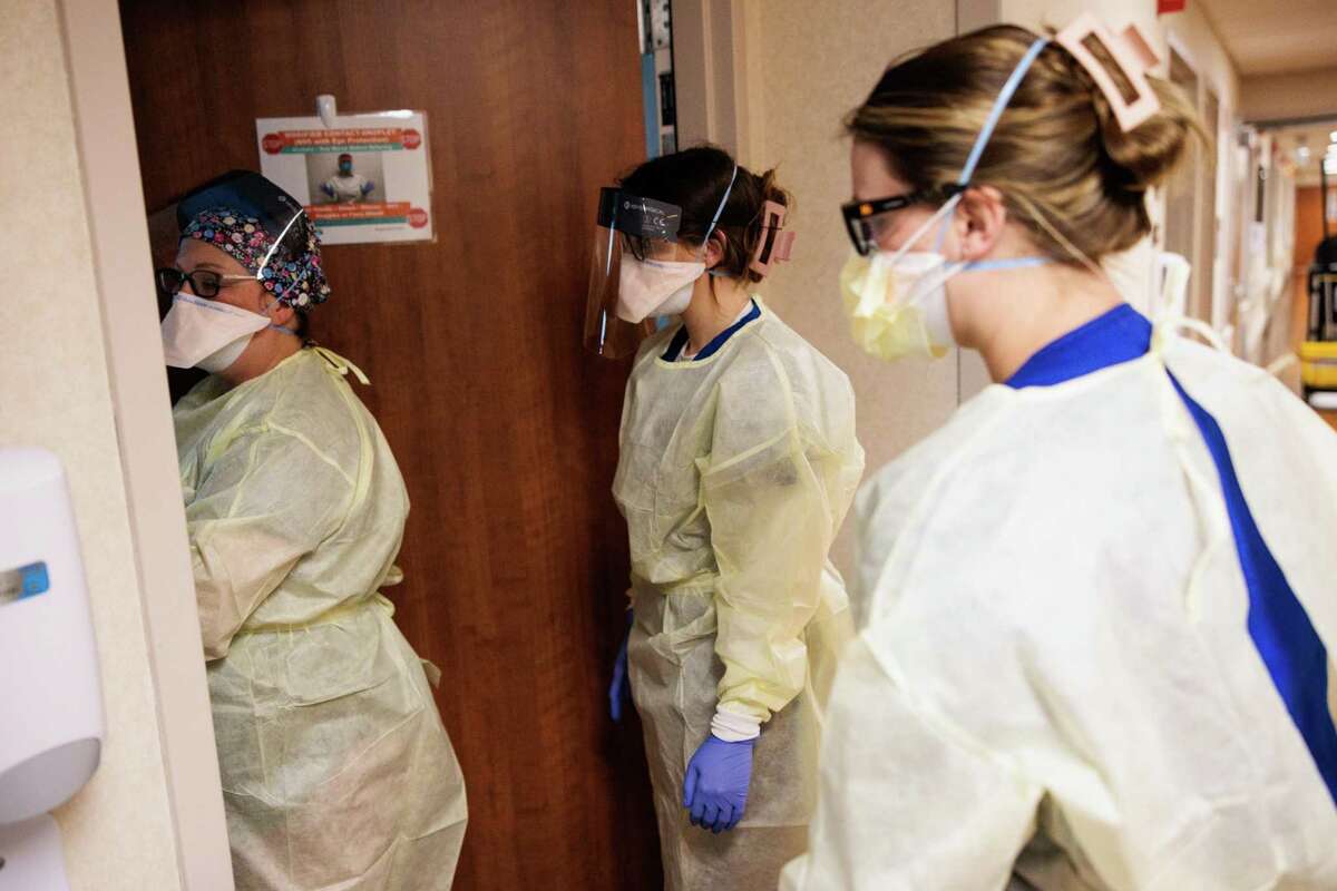 从左起，护士凯瑟琳·格雷和护理专业学生妮可·阿夫里特和拉奇·布朗特在加州索诺拉的基督复临健康医院检查一名新冠肺炎患者之前，穿上了个人防护装备。