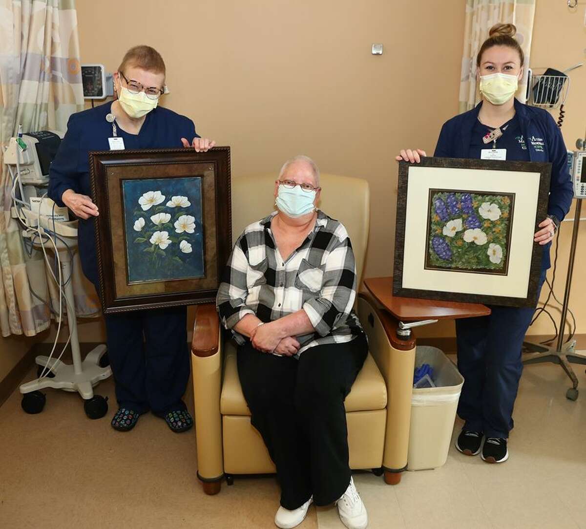 Elizabeth Denis (center) has plenty of artwork in the AMH Cancer and Infusion Center. Nurses Rachel Smith, left, and Allyson McGovern show off just a small portion of it.