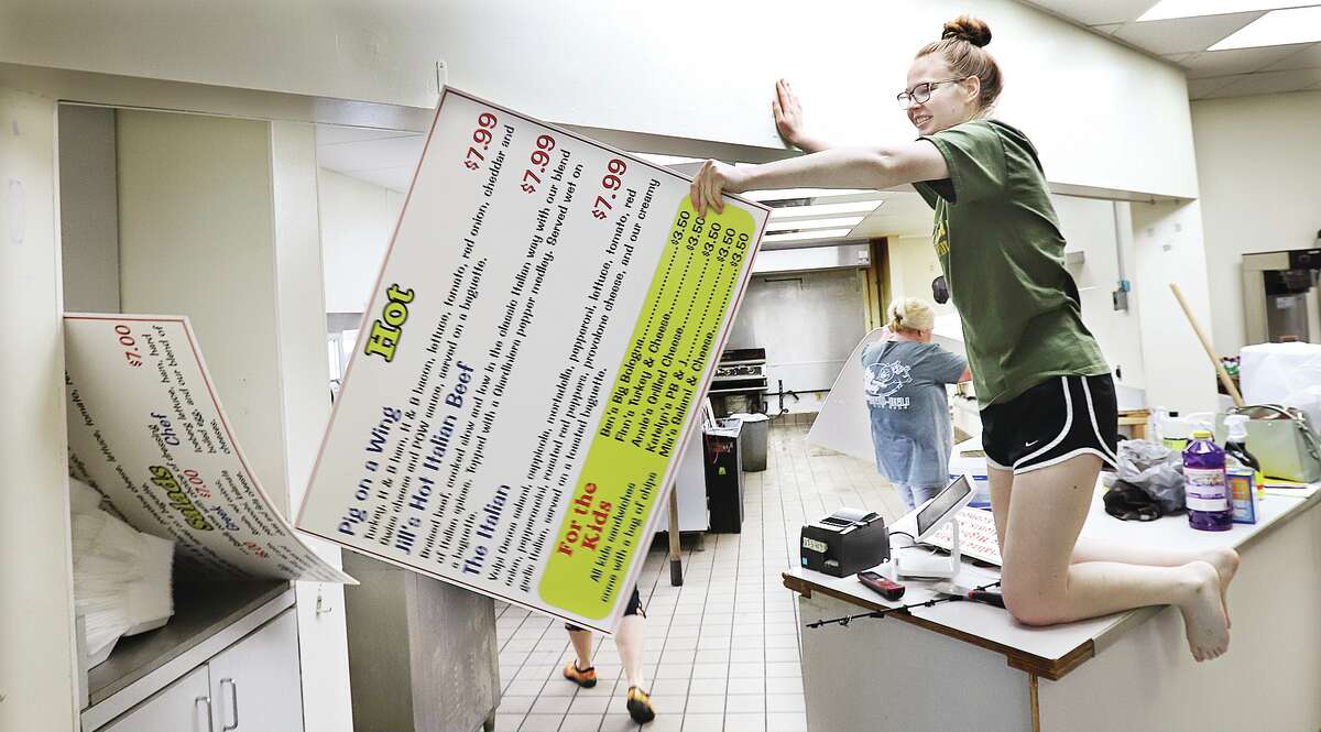 John Badman|The Telegraph Katelyn Krueger on Friday removes signage inside the Pig on a Wing that has just closed inside Metford's Food Mart at 216 Statet St. in Jerseyville. The popular eatery is moving back to its former Jerseyville location at 807 Illinois 16.