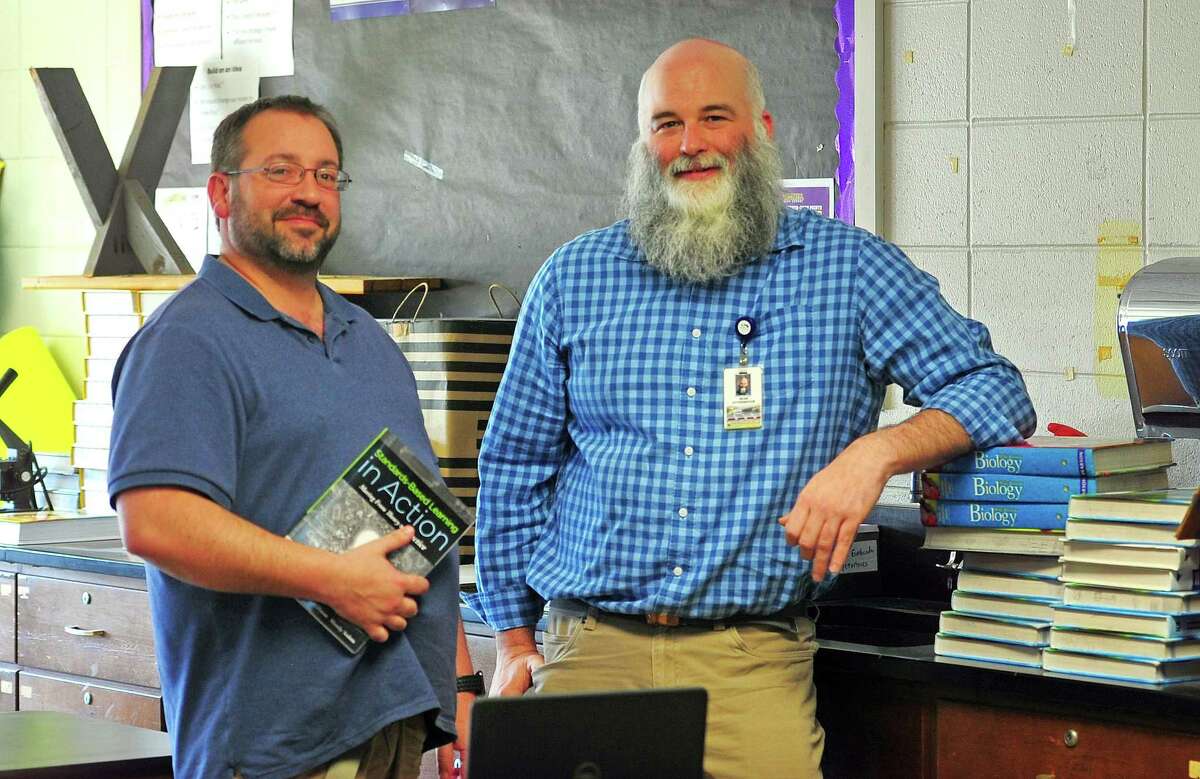 Westhill High School teachers Michael Capriotti, left, and Sean Otterspoor pose at the school in Stamford, Conn., on Friday April 22, 2022. At the school, teachers like Capriotti, who teaches math, and Otterspoor, who teaches science, are taking part in a pilot program called Grading for Equity. The biggest change they implemented was a shift from the traditional 1-100 grading scale.