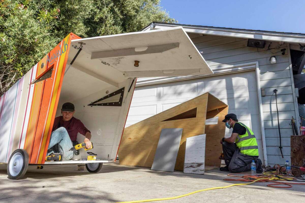 Volunteers Clayton Poon (left) and Alekz Londos work on building plywood shelters that will be offered to homeless people in Silicon Valley once finished. Costing $1,000 apiece, each mobile shelter has a web address or QR code for passersby to get more information about Simply Shelter, the grassroots project behind it.