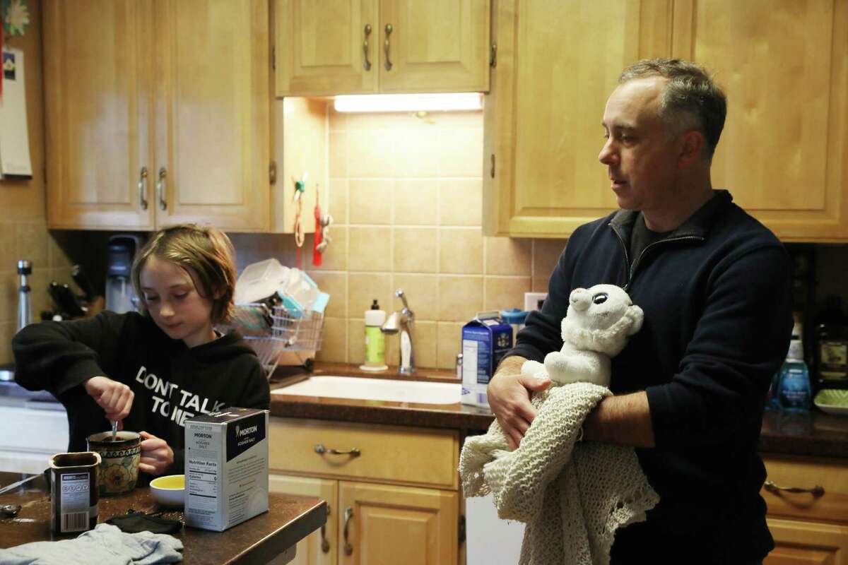 泰勒·斯特克尔(Tyler Sterkel)在厨房里和女儿玛蒂尔达(Matilda)聊天，手里拿着从盗窃中找回的物品。