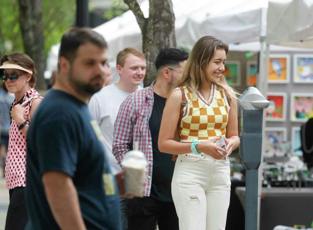 Visitors walk past booths during the annual Spring Fine Arts Show at Market Street, Saturday, April 30, 2022, in Conroe. Families browsed various art booths, enjoyed live music, and participate in artist demonstrations.