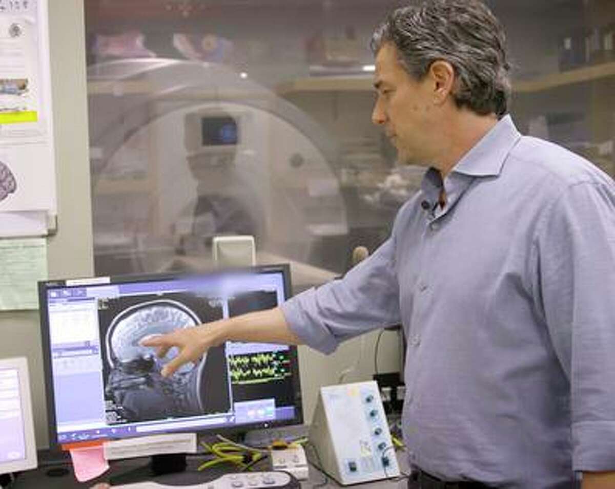 Dr. Daniel Abrams, the lead study author and a clinical associate professor of psychiatry and behavioral sciences, looks at a brain scan from the study on teenage neuroactivity.