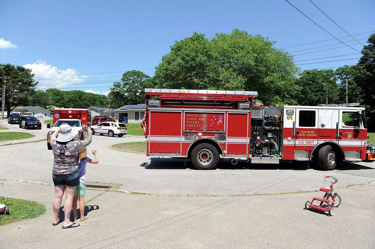 Sabrina Yoos and her daughter, Ellie, wave to Naval Submarine Base (SUBASE) New London fire vehicles as they drive past the Yoos’ home, in the Nautilus Park area of Beacon Point Homes, in honor of Ellie’s eighth birthday, June 12. The SUBASE New London Fire and Security Departments supported military family requests for special event parades during the COVID-19 stay-at-home orders.