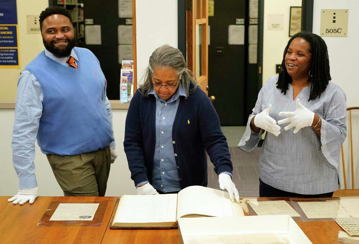 Phyllis Earles, archivist and head of special collections, center, brings out documents as Marco Robinson, left, and Melanye Price, right, talk about the Ruth J. Simmons Center for Race and Justice project studying the lives of the slaves who lived at Alta Vista Plantation that is now the grounds of Prairie View A&M University shown Monday, Jan. 24, 2022 in Prairie View.