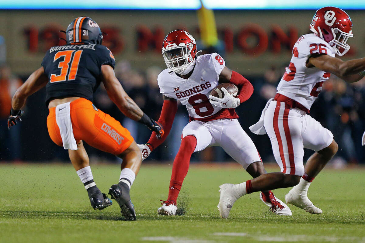 STILLWATER, OK - NOVEMBER 27: Wide receiver Michael Woods II #8 of the Oklahoma Sooners carries the ball against safety Kolby Harvell-Peel #31 of the Oklahoma State Cowboys in the first quarter at Boone Pickens Stadium on November 27, 2021 in Stillwater, Oklahoma. The Cowboys won 'Bedlam' 37-33. (Photo by Brian Bahr/Getty Images)