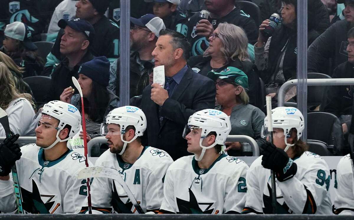 San Jose Sharks coach Bob Boughner, center, stands behind the bench during the third period of the team's NHL hockey game against the Seattle Kraken, Friday, April 29, 2022, in Seattle. The Kraken won 3-0. (AP Photo/Ted S. Warren)