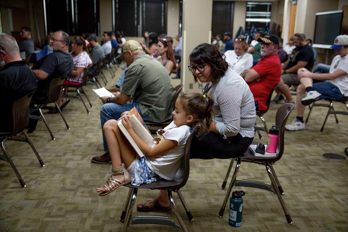 Eloise Christolear, a 3rd grader at NEISD’s Wilderness Oak Elementary School, reads with her mom, Katie Christolear, before the start of a contentious board meeting about masks last fall. They opposed requiring them but respected parents who wanted their children to wear them.