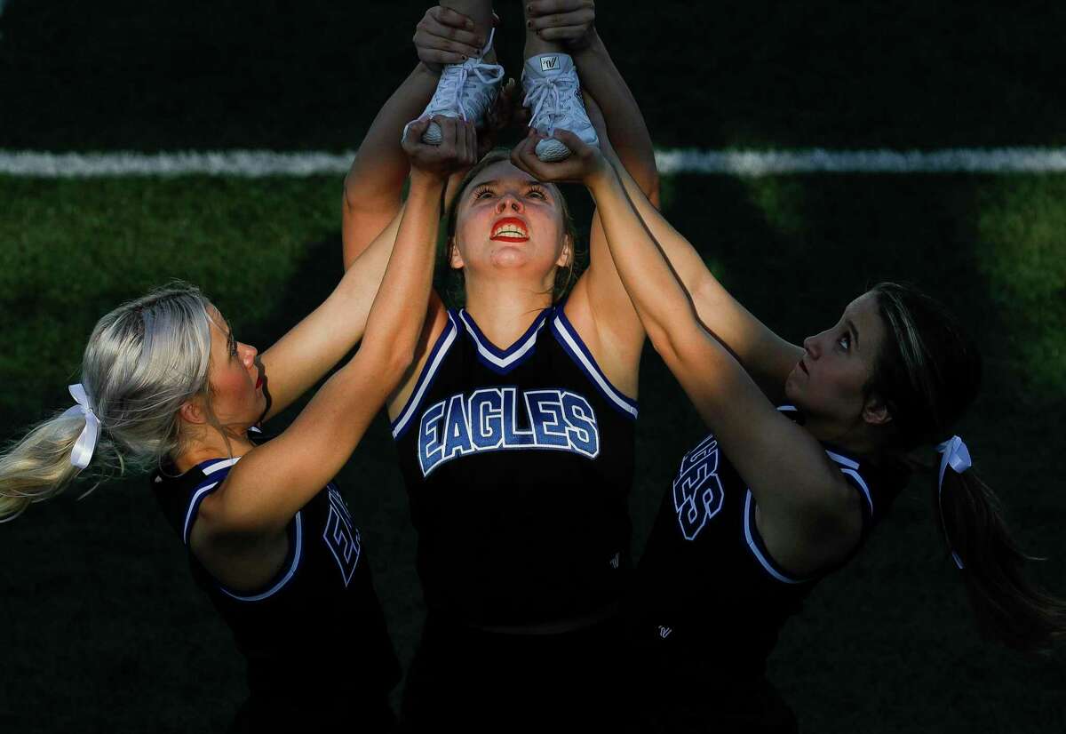 New Caney cheerleader Sierra Kenton, center, helps hold up a teammate before a high school football game at Randall Reed Stadium, Friday, Sept. 3, 2021, in New Caney. Photographer Jason Fochtman won first place feature photographer at the Texas Managing Editors conference for this photo.