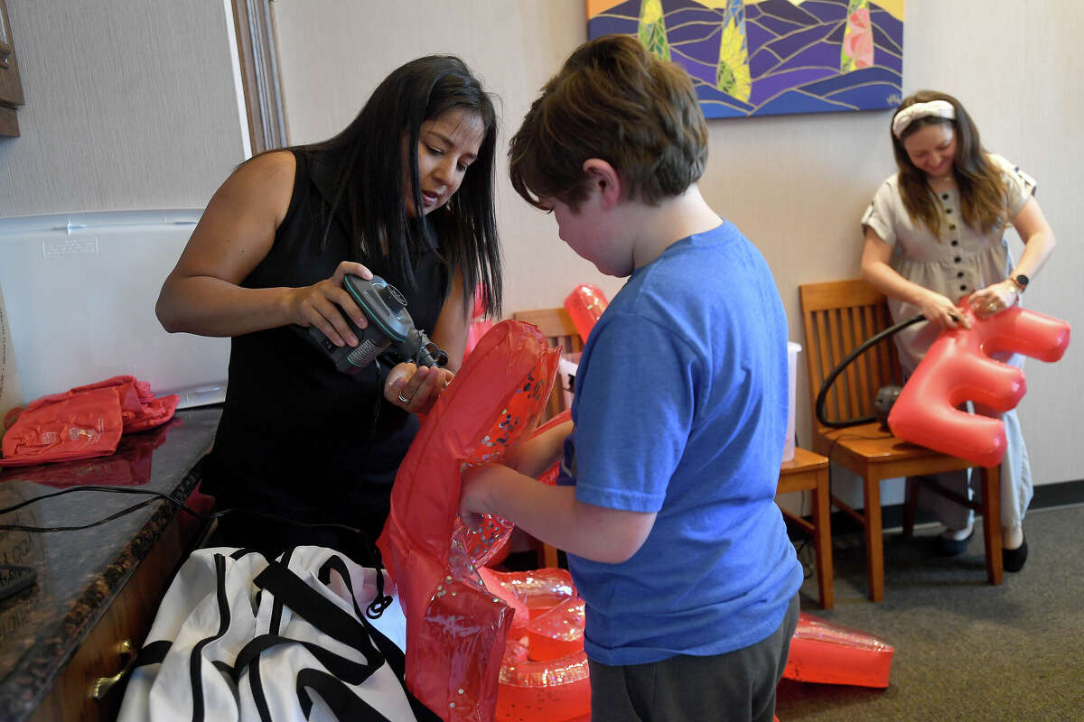 Susan Johnson helps Ezra Truncali blow up balloons as Sophia Bouey joins the efforts during a "working lunch" volunteer event at the Beaumotnt Convention and Visitor's Bureau to prepare for May's Artaco event, Photo made Thursday April 28, 2022. Kim Brent/The Enterprise