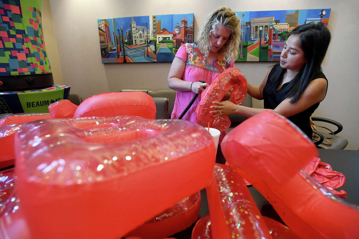 Susan Johnson (right) helps Sarah Wells get started blowing up balloons during a "working lunch" volunteer event at the Beaumont Convention and Visitor's Bureau to prepare for May's Artaco event. Photo made Thursday April 28, 2022. Kim Brent/The Enterprise