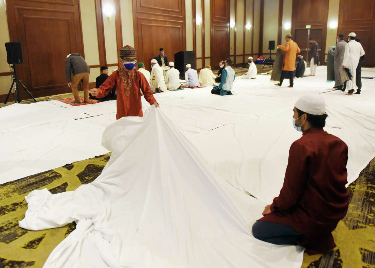 Stamford's Imran Vasanwala and Hasnain Shaikh, 11, lay down a sheet before the Eid al-Fitr prayer ceremony at the Hilton Hotel & Executive Meeting Center in Stamford, Conn. Monday, May 2, 2022. Presented by the Stamford Islamic Center, hundreds of Muslims gathered to break the fast and mark the end of the holy month of Ramadan.