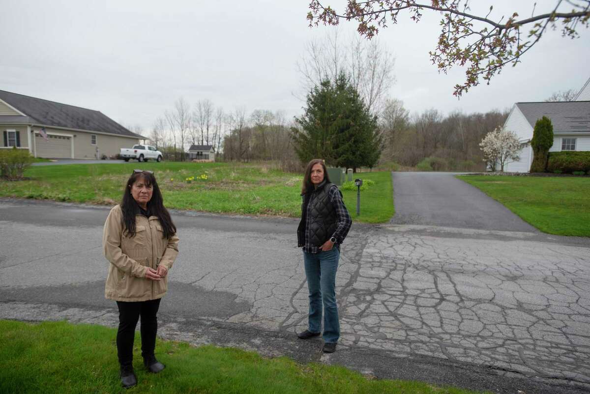 Neighbors, Angela Minkler, left, and Ann Glackin, stand across the street from their respective homes on Monday, May 2, 2022, in Malta, N.Y. The proposed Mountainview Meadows subdivision, would be built on farmland behind their homes. A connector road to the subdivision would run through the grass area seen behind the two women in the photo. Both women, along with many of their neighbors have concerns about traffic along with other issues if the subdivision is built. (Paul Buckowski/Times Union)