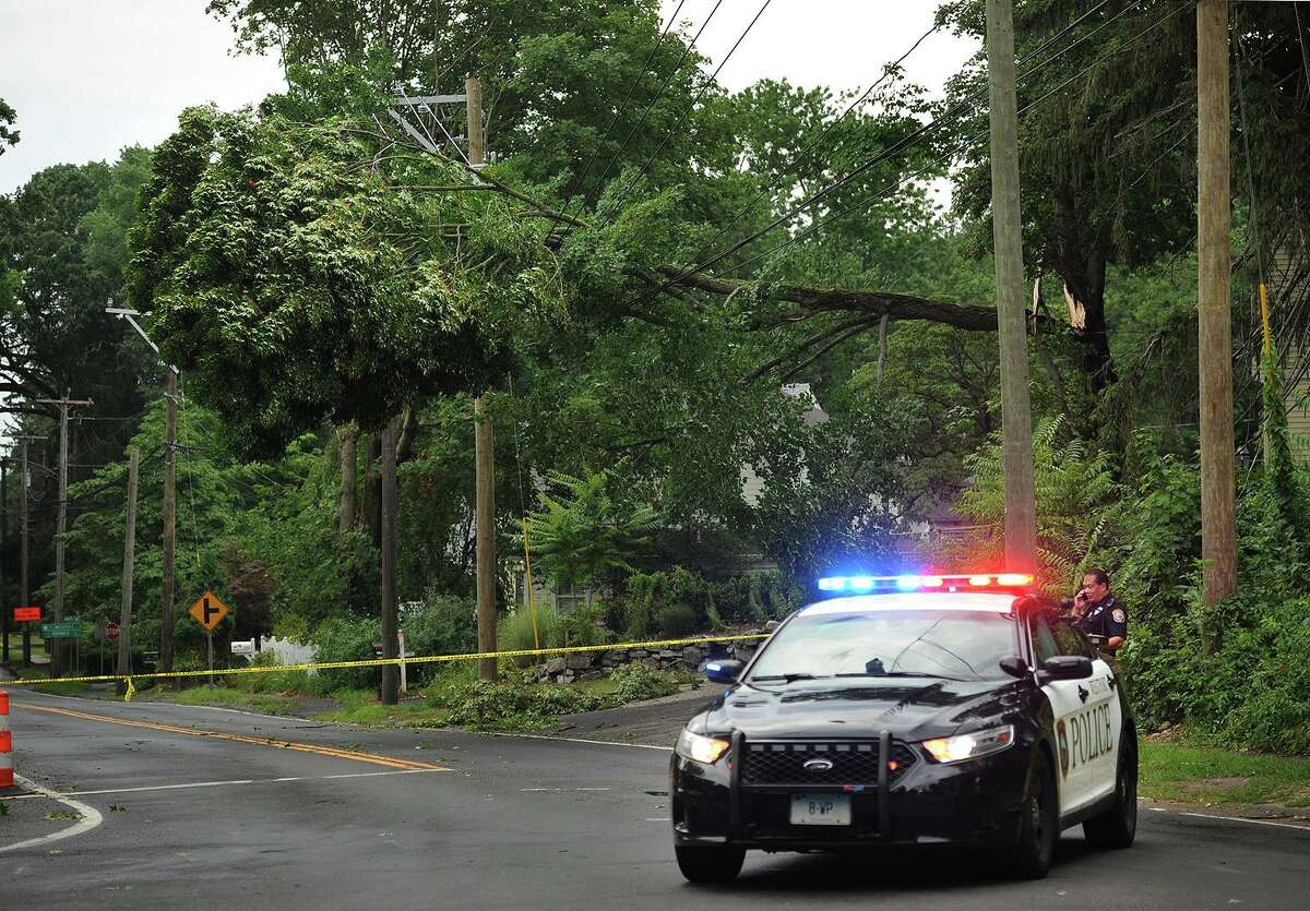 Westport Police close off a section of Main Street below the intersection with North Compo Road after a tree collapsed on overhead powerlines during afternoon storms in Westport, Conn. on Monday, July 18, 2016.