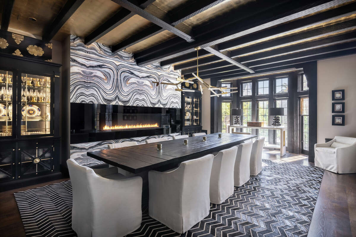 A very dramatic formal dining room is warmed by an oversized fireplace. 