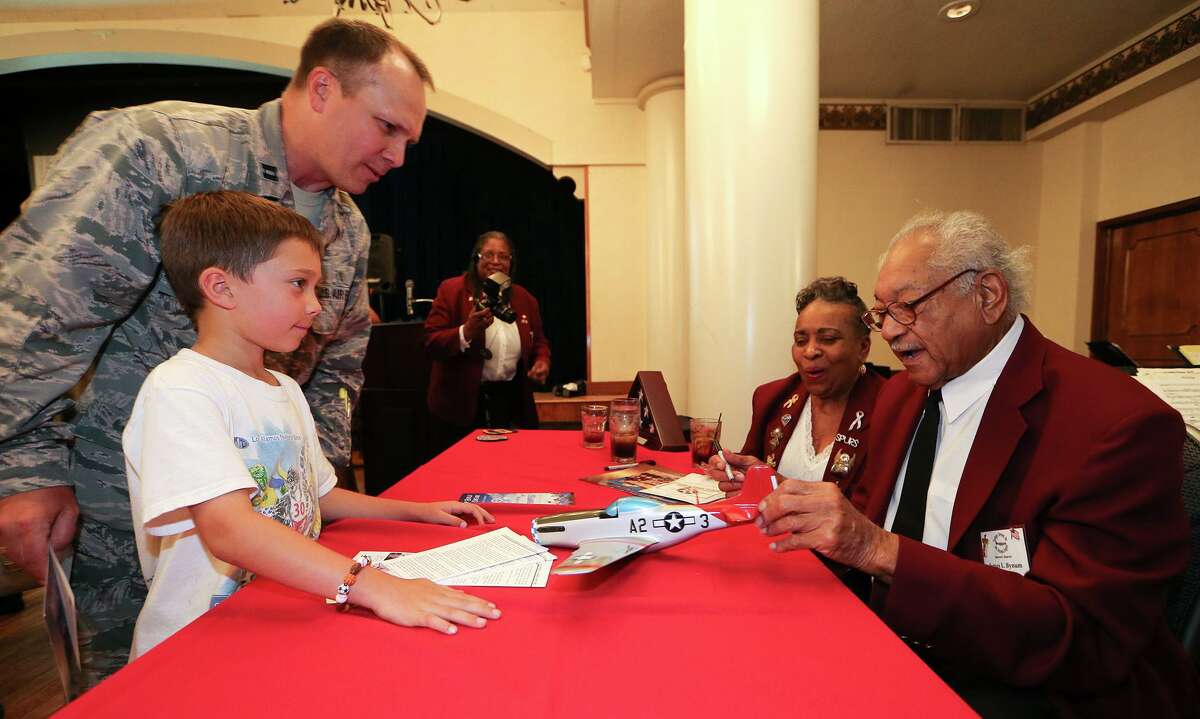 James Bynum, right, with his wife Dorothy, prepares to autograph a model of a P-51 Mustang for Jacob Wooten, 7, and his father, Air Force Capt. David Wooten, at a tribute to the Tuskegee Airmen at Joint Base San Antonio-Randolph in 2015.