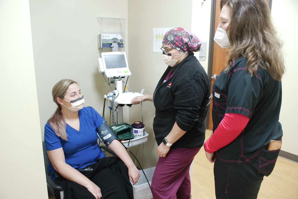 Nydia Stenger, RN, right, stands with Sandra Salazar who measures the blood pressure of Caitlyn Navarro at University of Texas Medical Branch CBC Webster Multispecialty Clinic.