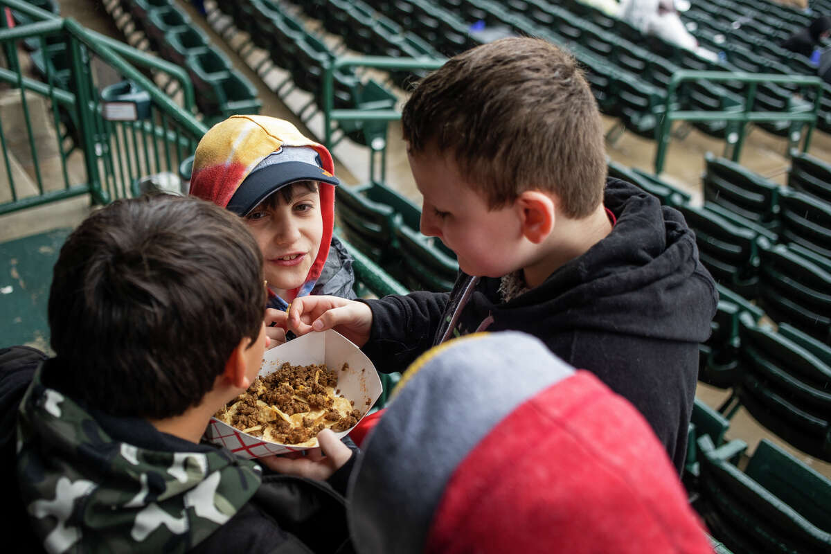 From left, All Saints Central Elementary students Marco Ramos, 11, Jacob Schatzer, 11, and Jace Blackwell, 11, huddle around a plate of nachos during School Kids Day presented by Central Michigan University Tuesday, May 3, 2022 at Dow Diamond in Midland. The Great Lakes Loons vs. Beloit Sky Carp game was eventually canceled due to rain.