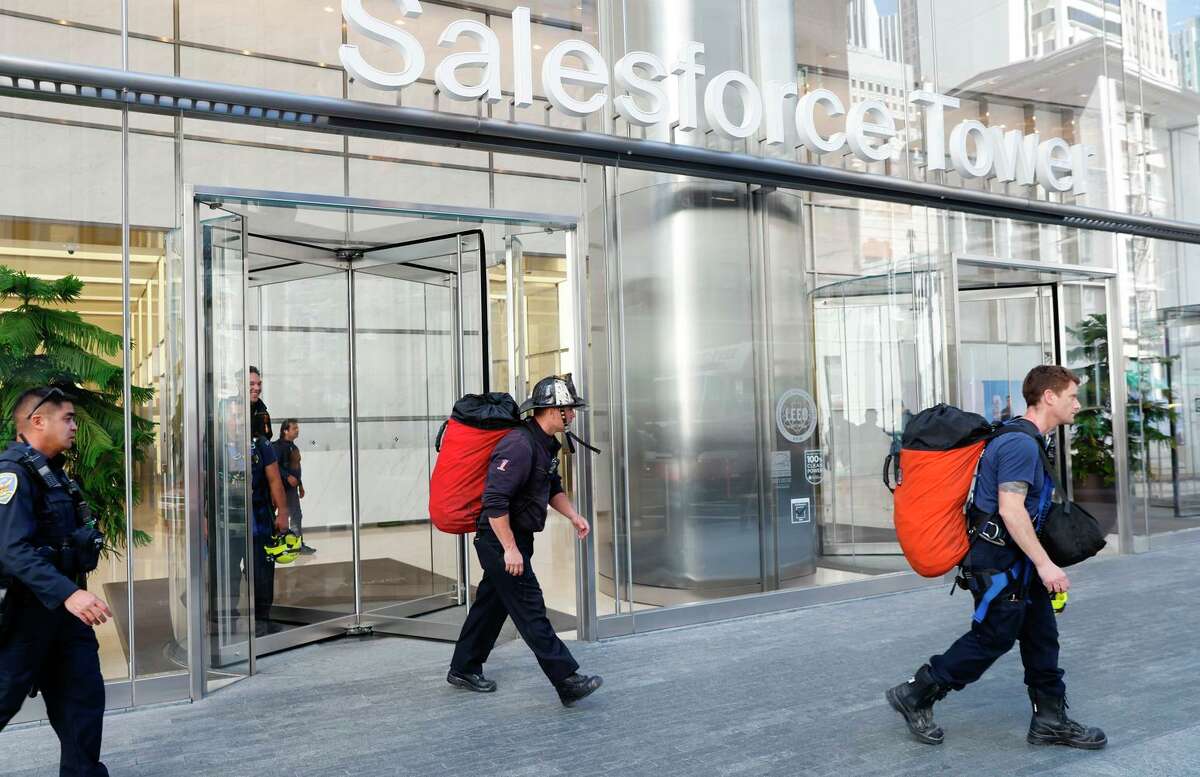 Firefighters and police officers exit Salesforce Tower after officials said a man who climbed the 60-story tower was arrested in San Francisco, Calif.