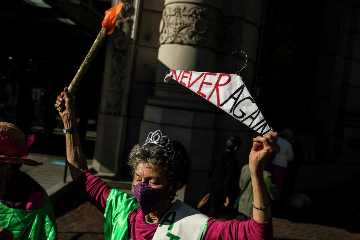 Susan Witka of San Francisco holds a sign on a hanger during a protest at the Powell and Market cable car turnaround after news the Supreme Court had likely decided to overturn Roe v. Wade.