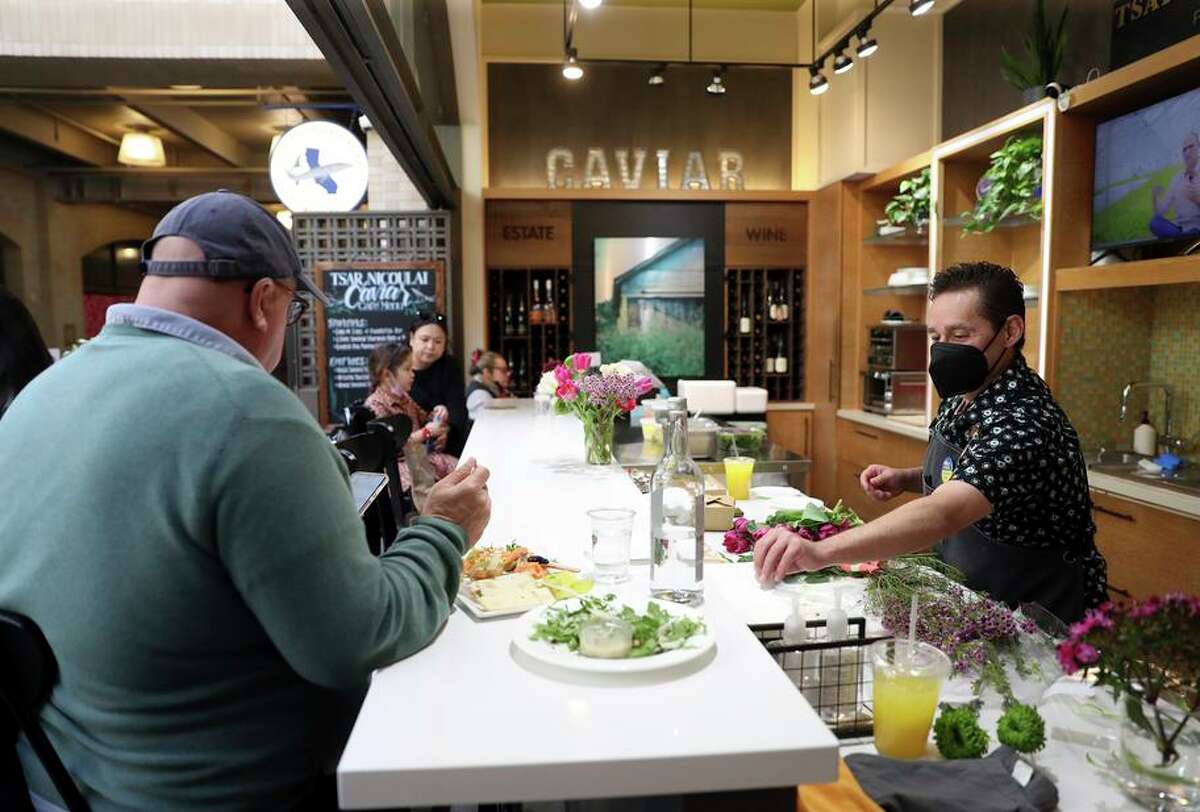 Tim Harper, right, prepares an order at Tsar Nicoulai Caviar’s cafe at the Ferry Building in San Francisco. He often fields diner questions about the company’s name.