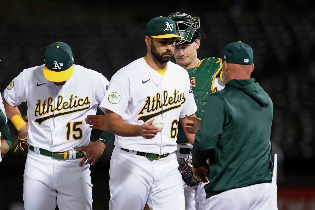 Oakland Athletics pitcher Lou Trivino, middle, hands the ball to manager Mark Kotsay as he is removed during the 10th inning of the team's baseball game against the Tampa Bay Rays in Oakland, Calif., Tuesday, May 3, 2022. (AP Photo/Jeff Chiu)