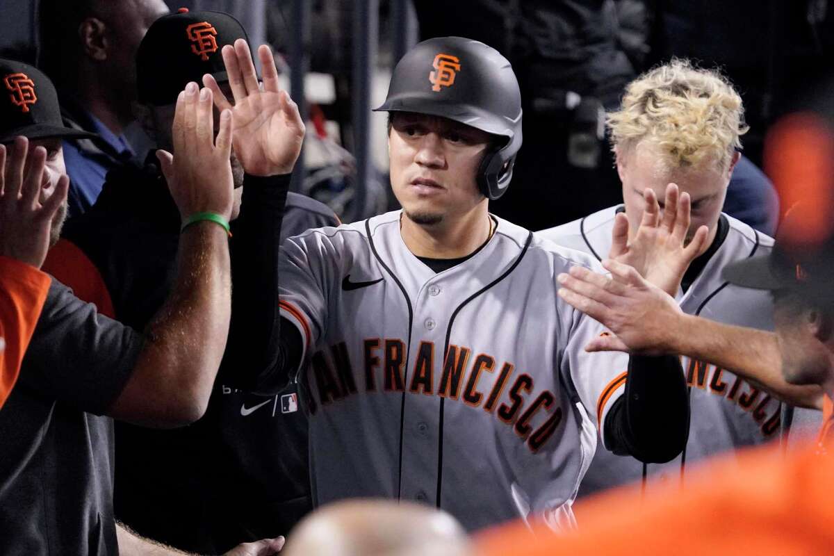 San Francisco Giants' Wilmer Flores is congratulated by teammates in the dugout after scoring on a sacrifice fly hit by Luis Gonzalez during the seventh inning of a baseball game against the Los Angeles Dodgers Tuesday, May 3, 2022, in Los Angeles. (AP Photo/Mark J. Terrill)