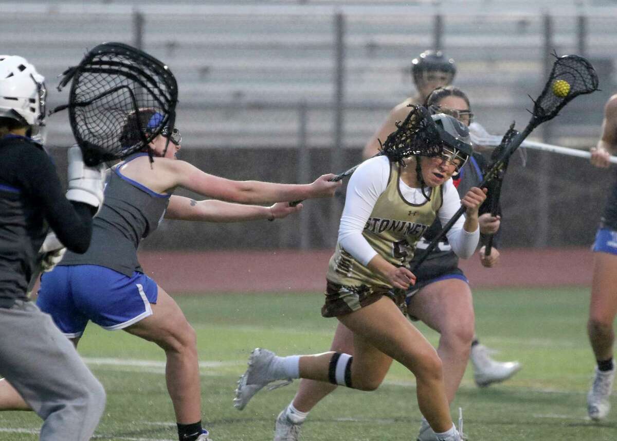 Stonington’s Lauren Gobble gets a stick to the side of her head against Waterford during the first half at Stonington High School, Tuesday, April 26, 2022. Stonington is the only school in Connecticut which requires headgear.