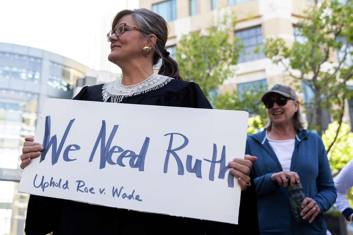 Alexandra Murphy, of Oakland, dresses as former Supreme Court Justice Ruth Bader Ginsburg while attending a protest outside of the Ronald V. Dellums Federal Building in Oakland, Calif., Tuesday, May 3, 2022, in response to the leak of a draft opinion on a potential Supreme Court vote to overturn Roe v. Wade. 