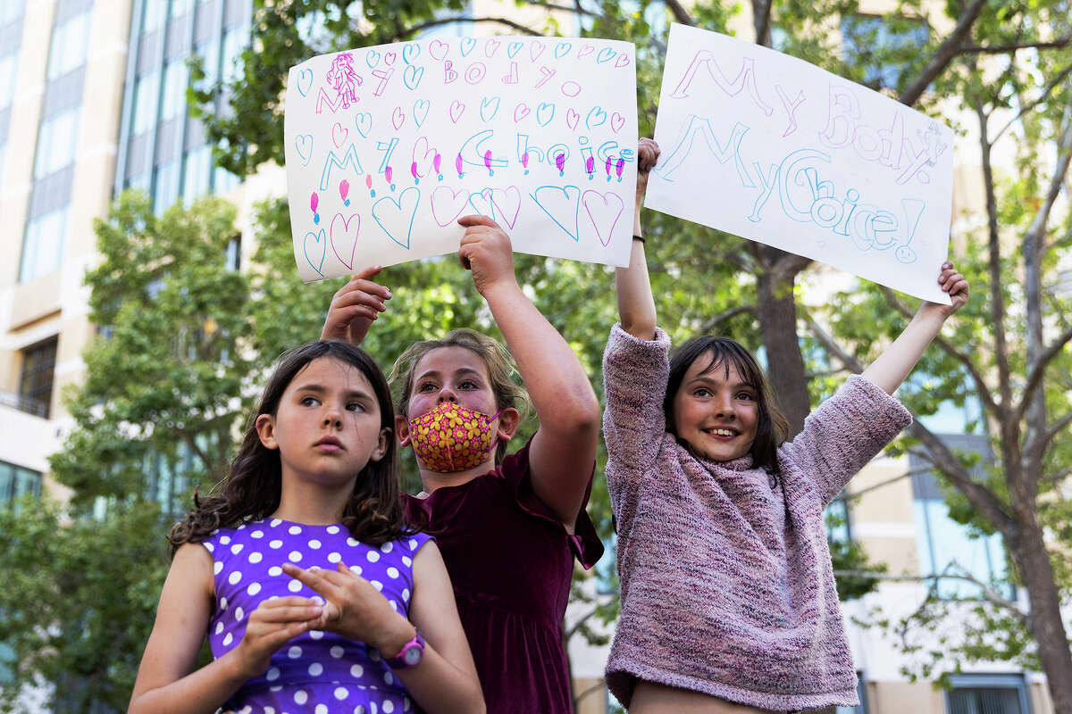 From left, Imogen McRae, 8, Aviva Shapiro, 9, and Saskia McRae, 10, carry signs while standing alongside abortion rights activists and supporters during a protest outside of the Ronald V. Dellums Federal Building in Oakland, Calif., Tuesday, May 3, 2022, in response to the leak of a draft opinion on a potential Supreme Court vote to overturn Roe v. Wade. 