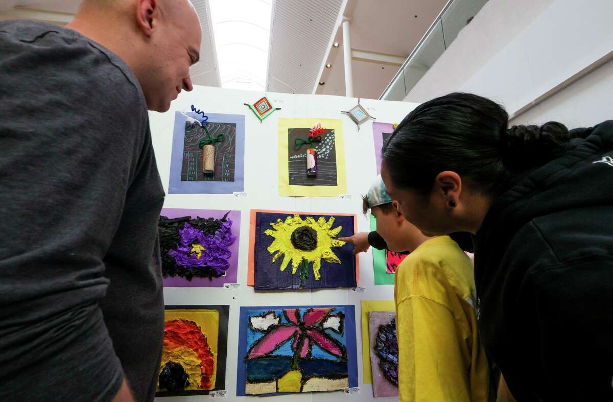 Tyler Hill, 10, a fourth-grader at Eloff STEAM Academy, shows his sunflower artwork to his parents, Liz Lucero, right and Brian Hill, at Art Extravaganza, Judson ISD’s annual district-wide art show, at Rolling Oaks Mall on April 27.