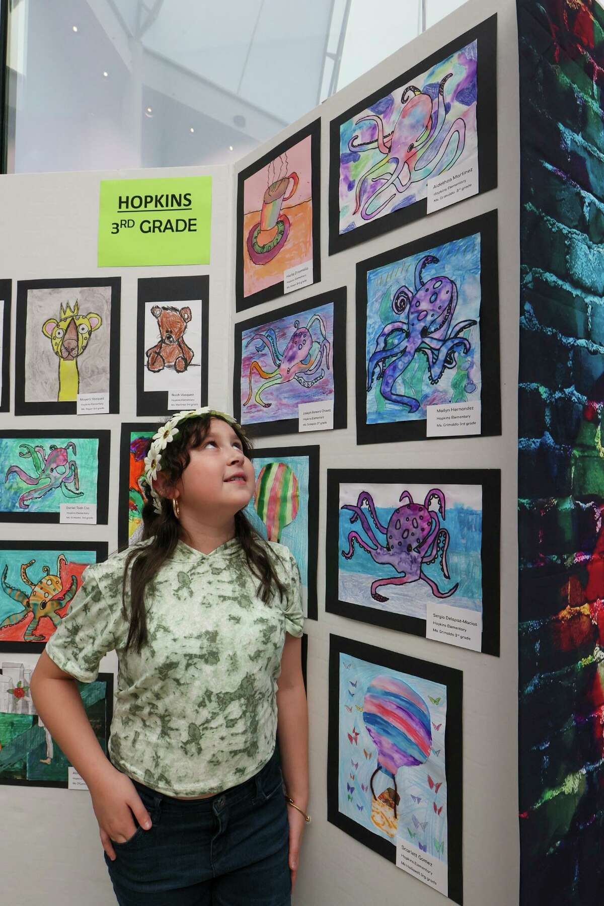 Aidethza Martinez, 9, a 3rd-grade student at Hopkins Elementary, looks at her octopus painting, top right, on display at Judson ISD’s Art Extravaganza last month at Rolling Oaks Mall.