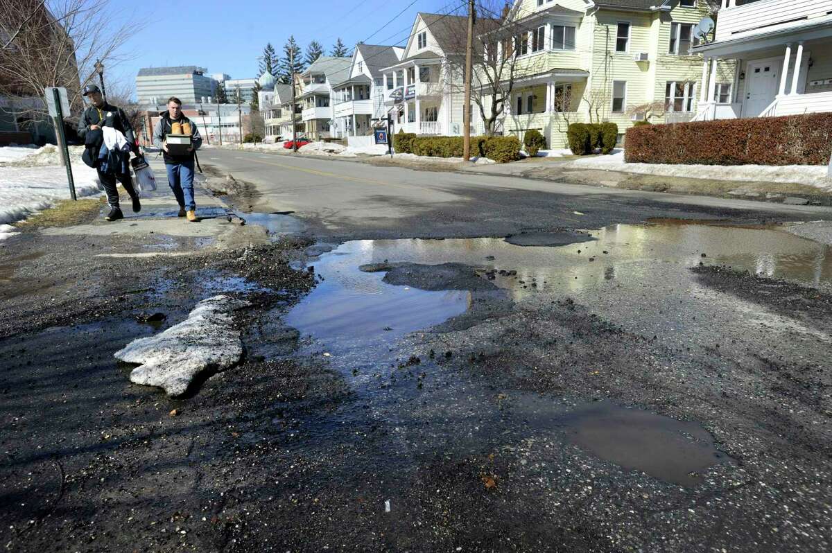 Potholes on Eighth Avenue in Danbury, Conn., are filled with water from melted snow, Thursday, March 12, 2015.