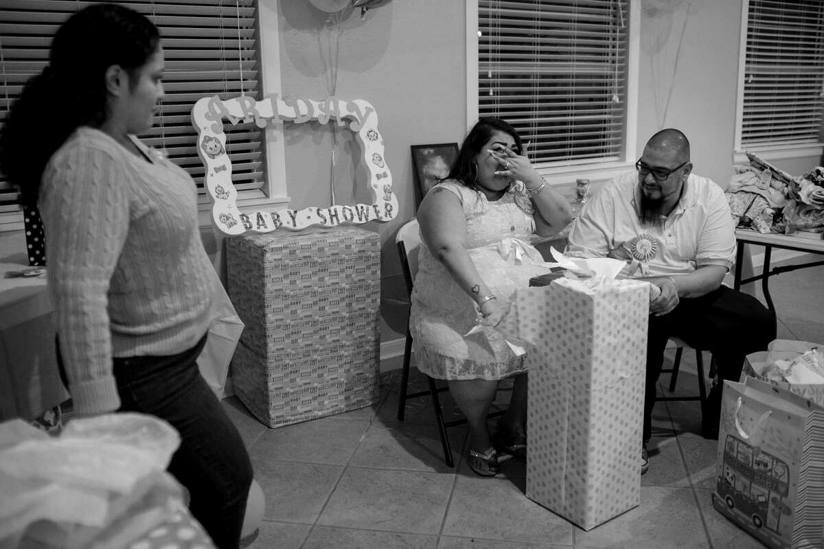 Maria Hernandez opens presents with her partner, Angel Espinoza, as they finish preparations for their baby shower. The couple had been trying to have a child for several years and were excited to celebrate the arrival of their daughter.