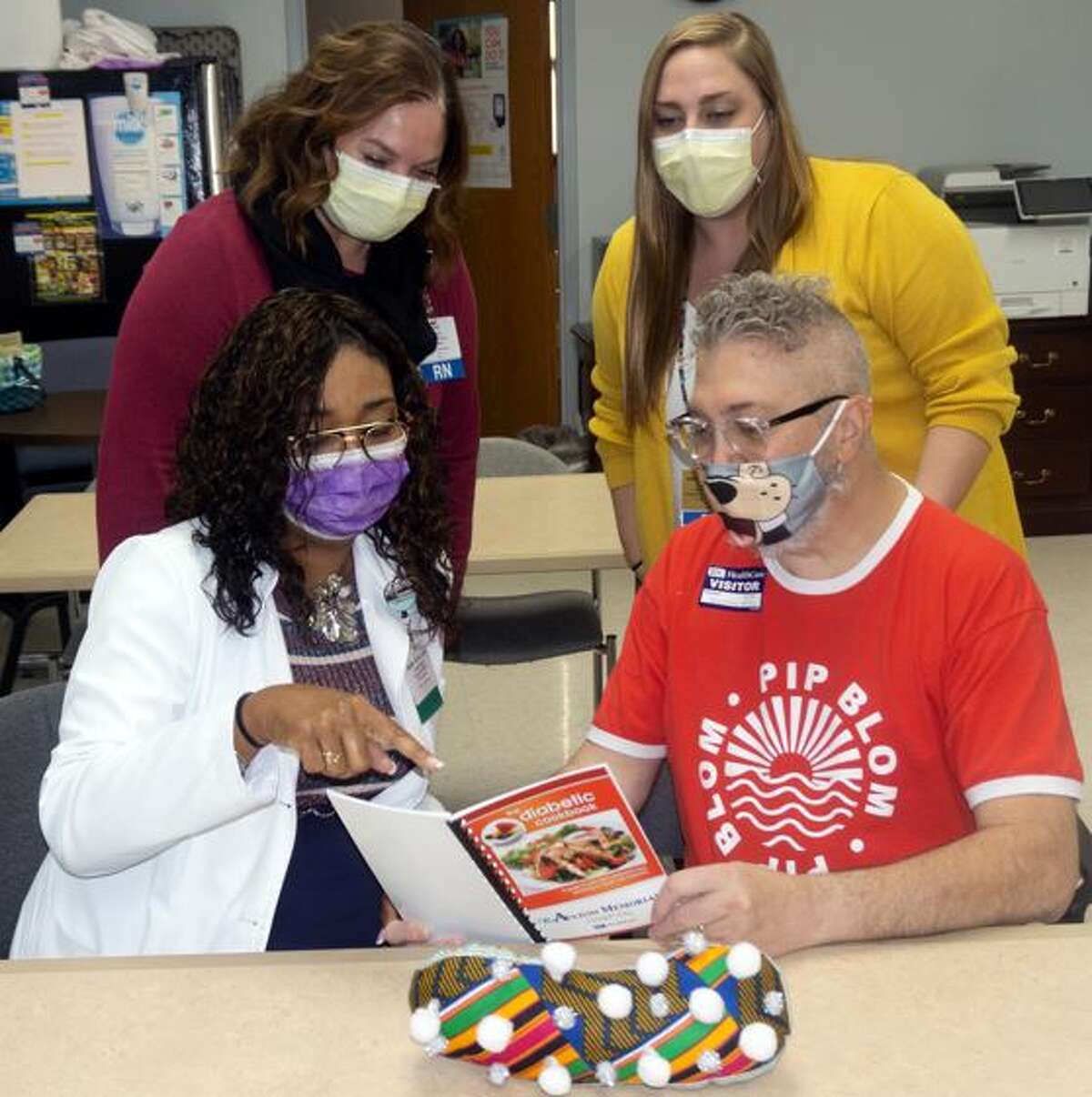Matt Contarino looks over a cookbook with recipes for diabetic patients with Alton Memorial Hospital registered dietitian Naomi Ward as well as (standing) Kathy Ridenhour and Kristin Cloninger of the Diabetes Management team. 