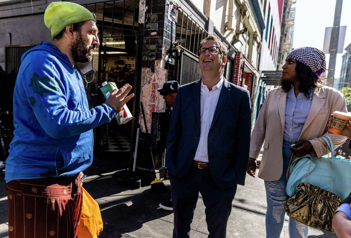 San Francisco Supervisor Dean Preston, center, laughs while chatting with a passing pedestrian during a walk in the Tenderloin neighborhood in San Francisco, Wednesday, May 4, 2022. Preston’s district 5, under the new redistricting plan, now covers Tenderloin.