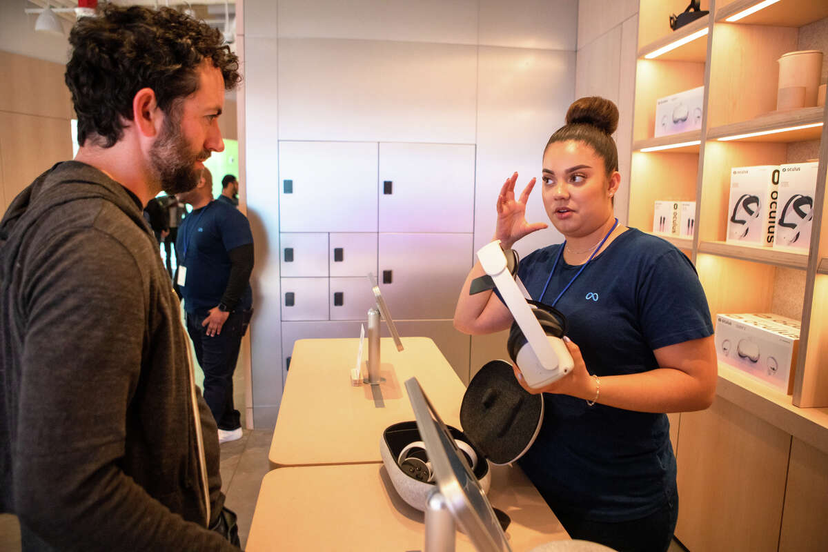 Meta Store employee Katie Contreras explains how to SFGATE culture editor Dan Gentile how to wear the Oculus Quest 2 virtual reality headset at the new Meta Store in Burlingame, Calif. on May 4, 2022.