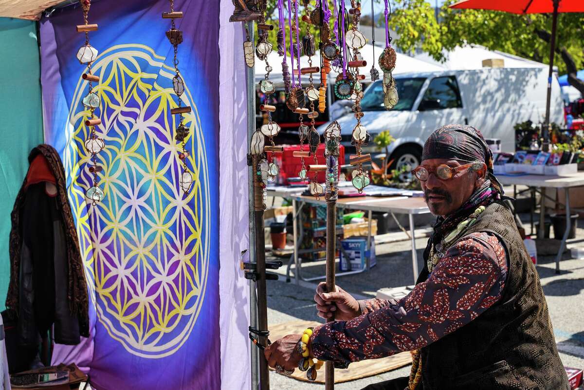 Magi, 75, organizes walking sticks at his Artifacts by Magi booth at the Berkeley flea market.