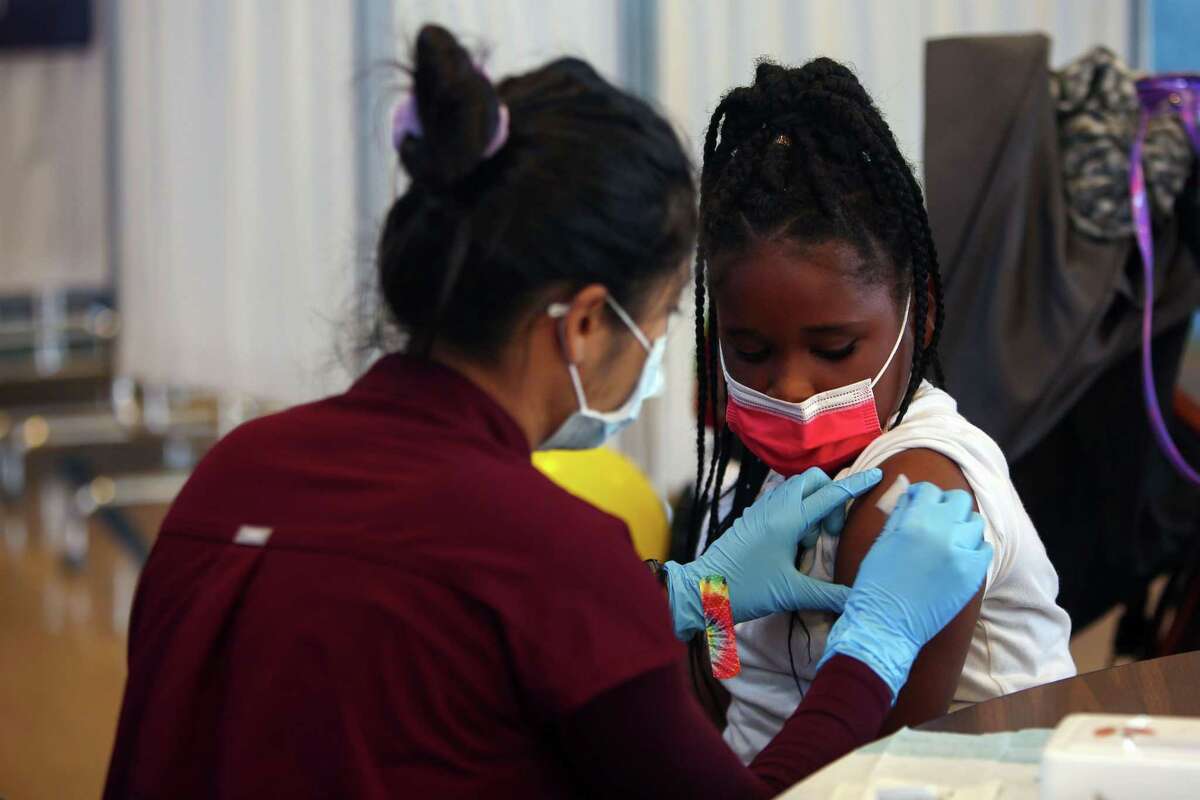 Unique Scott, age 7, sits as a nurse gives her a COVID vaccine shot in San Francisco.