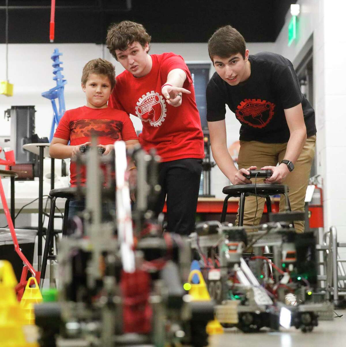 Nicklas De Tirro, center, coaches David Ballard, left, how to control a robot through an obstacle course beside Eric Dunleavy as members of The Woodlands High School’s robotics team hosted 18 students from Powell Elementary School as part of their outreach program, Pastabots Junior, Thursday, May 5, 2022, in The Woodlands. The after school program for elementary students, run by the TWHS robotics team, gives young students exposure to science and technology lesson and experiments.