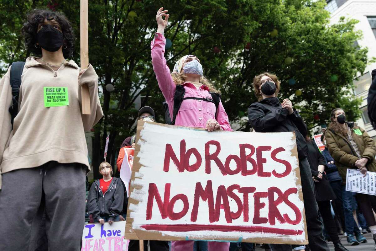 A person holds a sign that reads "No Robes, No Masters" during a "Rally to Defend Roe v. Wade" and "Stand up for Abortion and LGBTQ Rights" event in Seattle, Washington on May 3, 2022. - The Supreme Court is poised to strike down the right to abortion in the US, according to a leaked draft of a majority opinion that would shred nearly 50 years of constitutional protections. The draft, obtained by Politico, was written by Justice Samuel Alito, and has been circulated inside the conservative-dominated court, the news outlet reported. Politico stressed that the document it obtained is a draft and opinions could change. The court is expected to issue a decision by June. The draft opinion calls the landmark 1973 Roe v Wade decision "egregiously wrong from the start." (Photo by Jason Redmond / AFP) (Photo by JASON REDMOND/AFP via Getty Images)