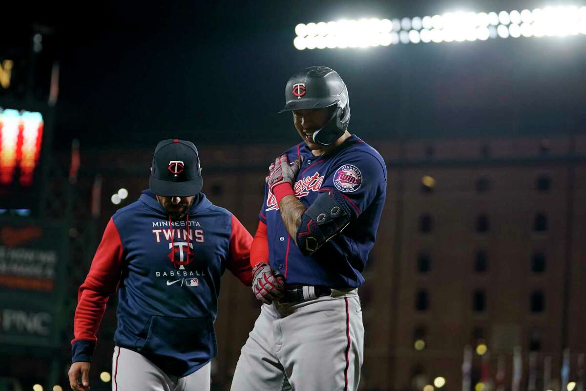Minnesota Twins bench coach Jayce Tingler, left, stands next to Carlos Correa after he was hit by a pitch from Baltimore Orioles starting pitcher Spenser Watkins during the fifth inning of a baseball game, Thursday, May 5, 2022, in Baltimore. (AP Photo/Julio Cortez)