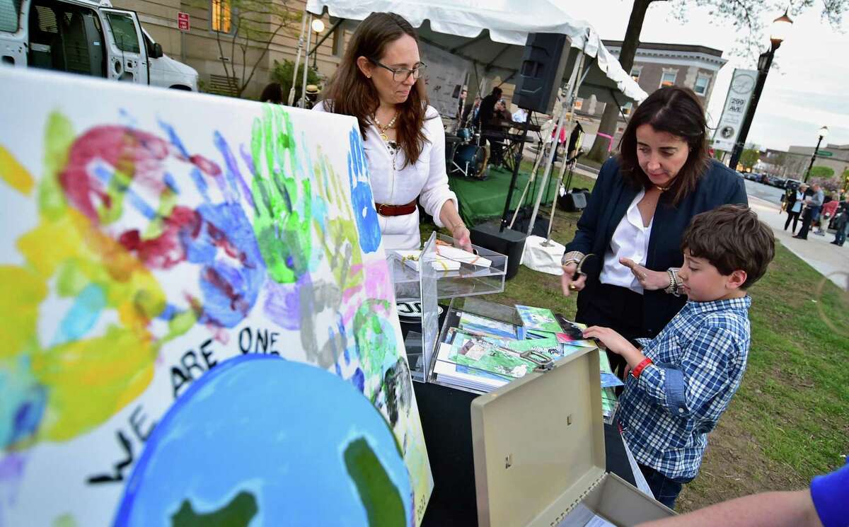 Antoinette Quigley and her son Max, 8, at right, pick out some art postcards on sale during the kickoff of the Greenwich Arts Council's 25th anniversary "Art to the Avenue" event held along Greenwich Avenue in Greenwich, Conn., on Thursday May 5, 2022. Art will be on display in businesses up and down Greenwich Avenue through May 31.